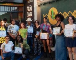 A group of 10 people holding certificates pose in front of a wall mural.