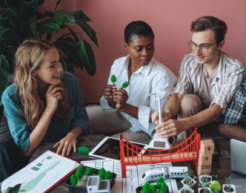 Adults converse around a table covered in model construction elements like wind turbines and rail transit.