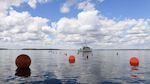 A lone boat out on the water with three red buoys