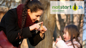 A smiling outdoor educator signs to a young child. NatStart24 logo in top right. 