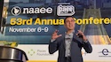 Dr. Vik Mohan speaks in front of a screen with the words "NAAEE 53rd Annual Conference, November 6–9."